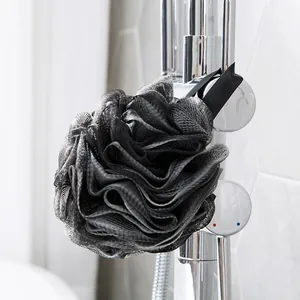 Premium large charcoal grey mesh bath sponge with soft lace trim hanging on chrome faucet