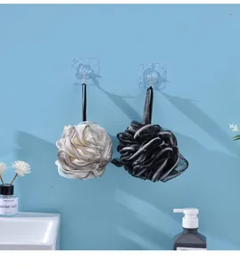 Close-up detail of gray and black bath mesh sponge balls hanging on bathroom wall hooks.
