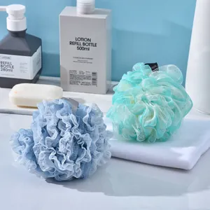 Two large soft mesh foaming bath loofahs in blue and green on a bathroom counter