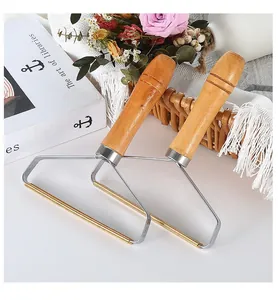 Macro detail of manual lint remover with ergonomic wooden handle and metal head