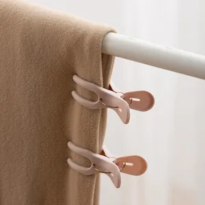 Close-up of pink plastic windproof clips securing a thick blanket to a white drying rack