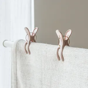 Detail view of pink rabbit-ear windproof quilt clips holding a thick white towel