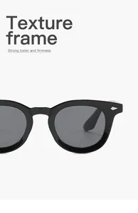 Close-up detail of retro black sunglasses with oval frame and silver rivet accents