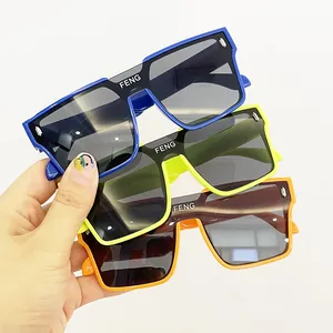 Mano che tiene tre paia di occhiali da sole quadrati oversize colorati per bambini.