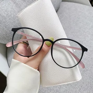 Close-up van zwarte ronde bril met roze poten op een luxe wit gestructureerd etui
