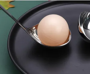 Close-up of a stainless steel long-handle soup spoon holding a round prop on a black tray