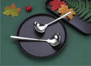 Detail view of two high-quality stainless steel soup spoons on a black plate.