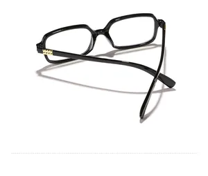 Detail shot of black square glasses frame with golden textured hinges on white background