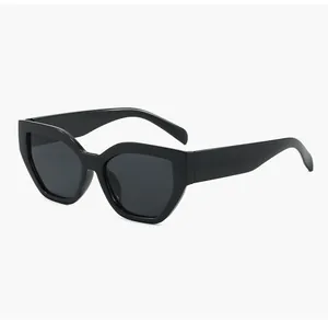 Dettaglio di occhiali da sole cat-eye neri oversize con montatura spessa e irregolare