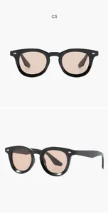 Macro view of black oval sunglasses with light brown lenses and decorative silver rivets