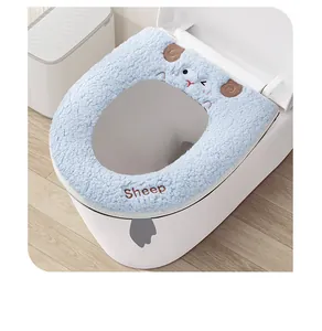 Detail view of a thick blue plush toilet seat cover featuring cute cartoon sheep embroidery