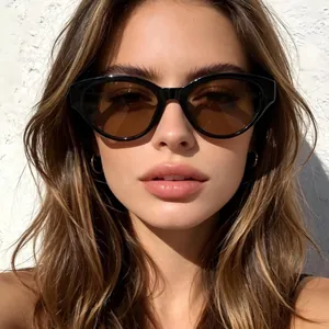 Stijlvolle zwarte cat-eye zonnebril met bruine glazen gedragen door een model voor een muur