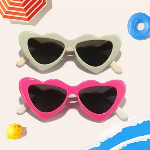 Pair of cute candy-colored heart sunglasses for kids on a beach theme background