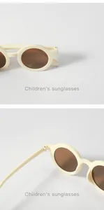 Close-up detail of stylish beige children's sunglasses with brown lenses and round frame