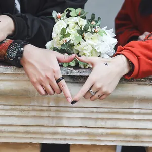 Minimalistische geometrische titanium stalen ringen voor koppels die een hart vormen met handen.