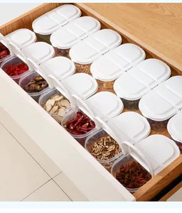 Set of white-lid plastic spice containers organized in a wooden kitchen drawer