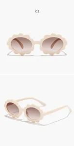 Detailed macro view of cream flower-shaped sunglasses for kids with brown gradient lenses