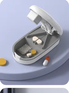 Detailed interior view of a white portable pill cutter and crusher with medication samples
