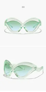 Detailansicht der futuristischen übergroßen Cat-Eye-Sonnenbrille mit grünem Rahmen.