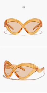 Nahaufnahme einer übergroßen futuristischen Cat-Eye-Sonnenbrille mit bernsteinfarbenem Rahmen.