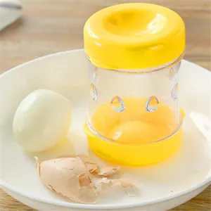 Close-up of manual yellow egg peeler shaker tool with a peeled egg in a white bowl