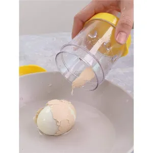 Action shot of hand-held egg sheller removing shells from a boiled egg into water.