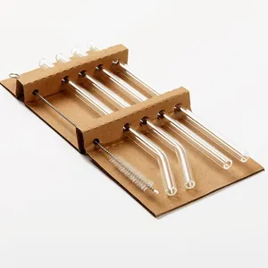 Reusable clear borosilicate glass straw set with cleaning brush on cardboard base.