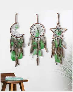 Detail view of three handmade green feather dreamcatchers hanging on a white wall.