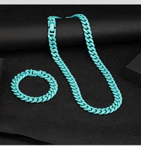 Bright cyan Cuban link necklace and bracelet set on black textured background