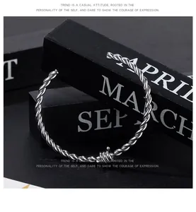 Detail of a silver twisted titanium steel cuff bracelet with central knot design.