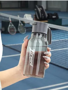 Gros plan d'une bouteille d'eau de sport en plastique PCTG grise tenue sur un court de tennis.
