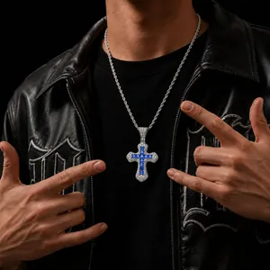 Dettaglio di un ciondolo a croce con zirconi blu e bianchi stile hip hop moderno.