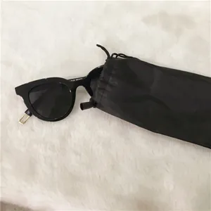 Macro view of black fiber drawstring storage pouch with sunglasses on white faux fur background