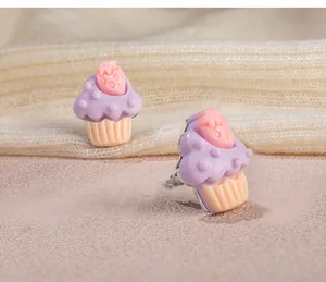 Detailansicht süßer Erdbeer-Cupcake-Ohrringe mit lila Glasur und weichem Hintergrund