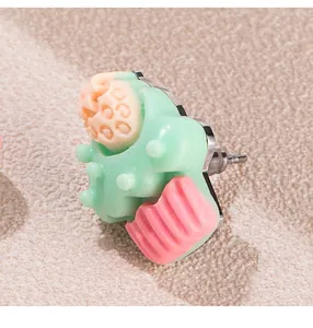Detaillierte Nahaufnahme eines süßen mintgrünen und rosa Erdbeerkuchen-Ohrsteckers.