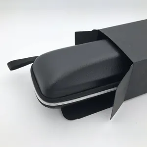 Detail view of the black portable eyeglass case partially inside its black cardboard box.