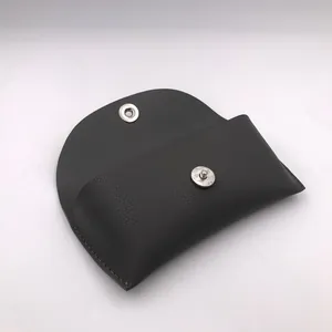 Detail view of the pebbled leather texture and magnetic snap on this black glasses case.