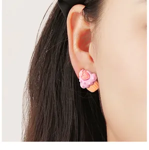Detailansicht eines niedlichen rosa Erdbeer-Cupcake-Ohrsteckers, am Ohr getragen.