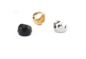 Anillos geométricos robustos y polifacéticos en acabados negro oro y plata sobre fondo blanco