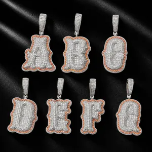 Close-up detail of iced out bone alphabet pendants with orange zircon border accents