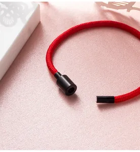 Detailopname van een rode gevlochten armband met een zwarte magnetische sluiting