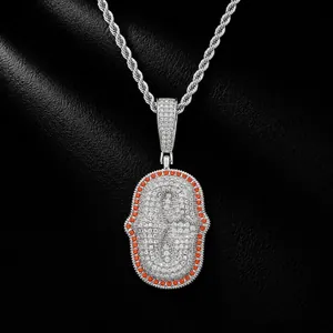 Close-up of hip hop pendant with white pave-set zircons and orange stone border.