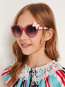 Young girl wearing sparkly pink round children's sunglasses with a white bow detail