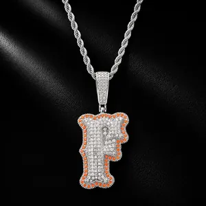 Detailed macro view of iced out bone-shaped letter F pendant with orange stones.