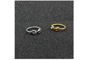 Makrodetail von minimalistischen Knotenringen in Gold und Silber auf schwarzem Grund.