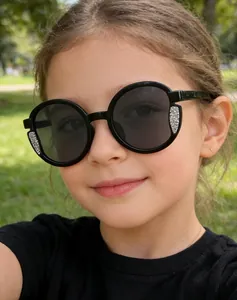 Bambina alla moda che indossa occhiali da sole rotondi neri con glitter argento.