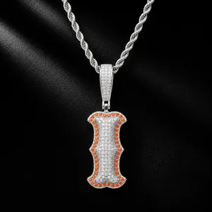Close-up detail of hip-hop bone-shaped letter I pendant with orange and white CZ stones