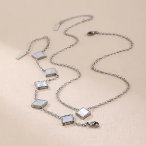 Macro detail of silver titanium steel necklace featuring geometric square mother of pearl