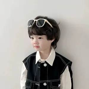 Detailed view of a young child wearing foldable beige sunglasses with UV protection lenses