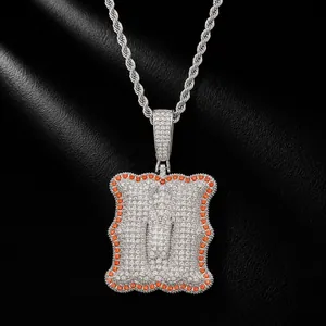 Detailed view of iced out silver letter U pendant with orange stones on rope chain